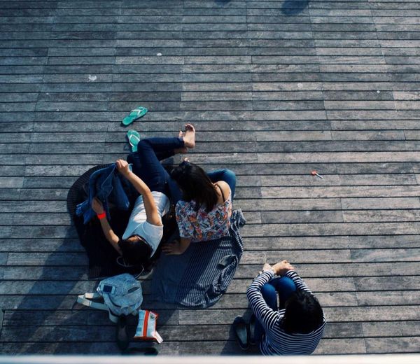 Friends lying together on a sunny wooden dock, seen from above